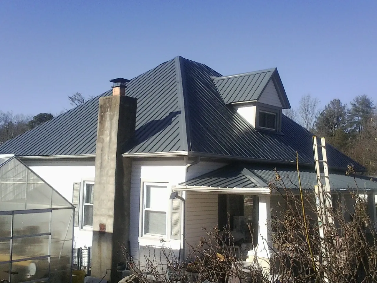 Dark blue standing seam metal roof on a white farmhouse with dormer — Slate & Tile Roof Repair by Roofing Brothers in Lake Waccamaw