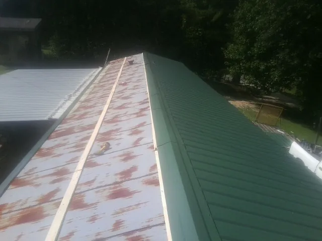 Old rusted panels beside newly installed green metal roofing — Wind Damage Roof Repair by Roofing Brothers in Lake Waccamaw