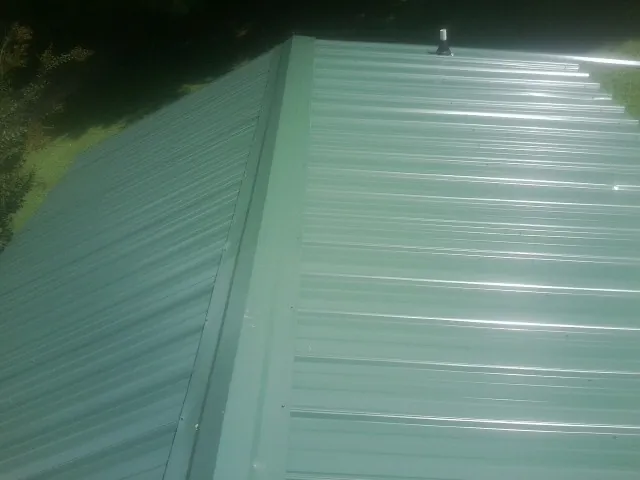 New green metal panels meeting at the ridge of a roof — Flat Roof Repair work by our crew in Lake Waccamaw