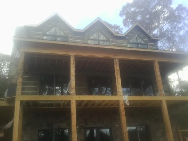 Dormers and porch framing on a large log home under construction — Roof Coating work by our crew in Lake Waccamaw