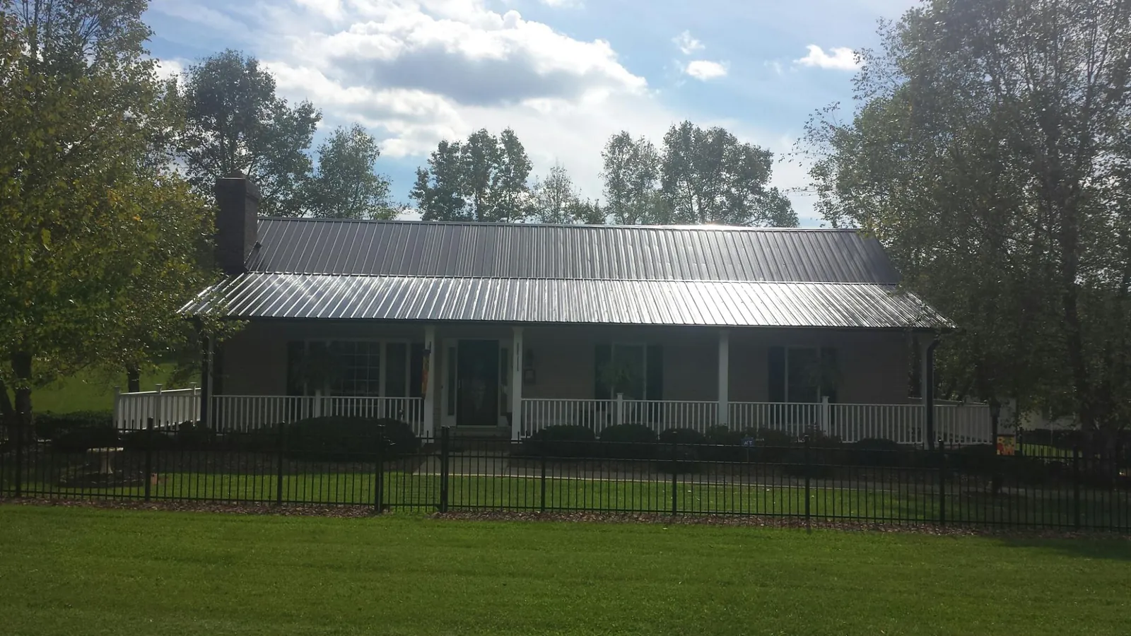 Gray metal roof on a brick ranch with a full width front porch — Gutter Guard Installation work by our crew in Lake Waccamaw