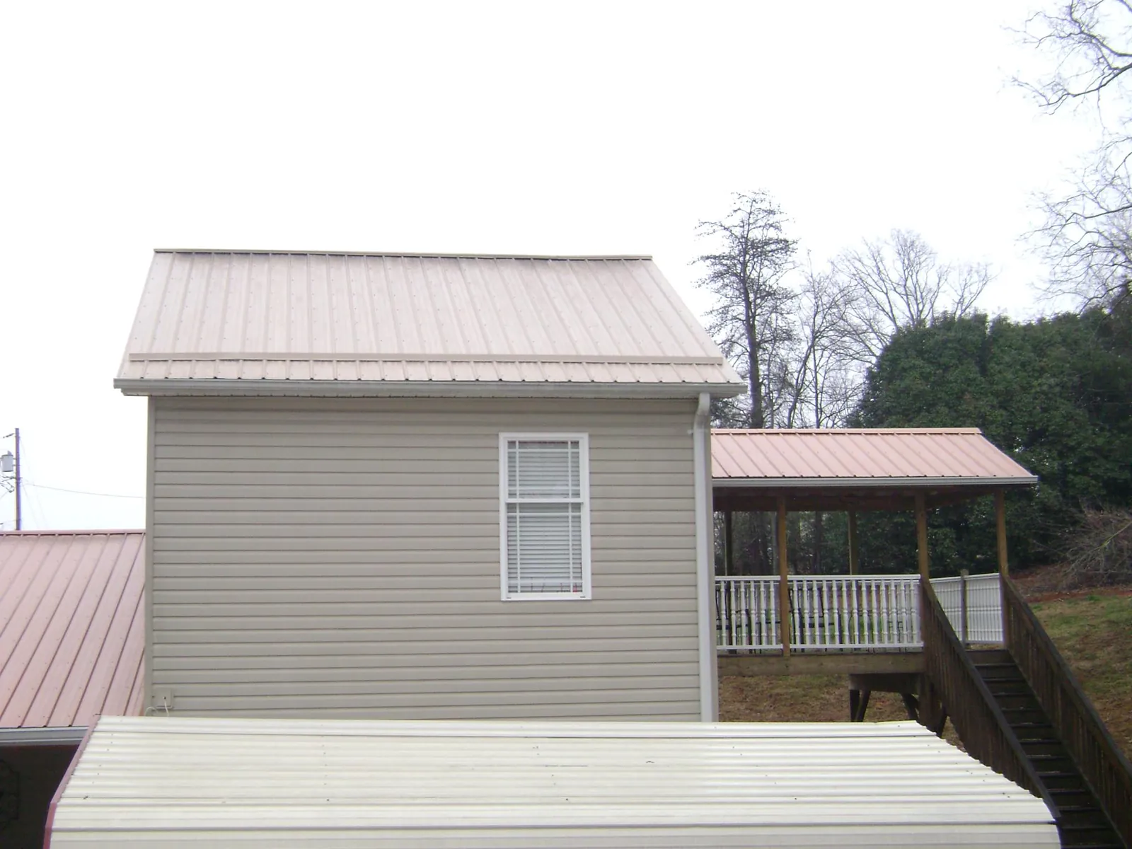 Tan metal roofs on a two story addition and attached porch, from a Roof Replacement job in Lake Waccamaw