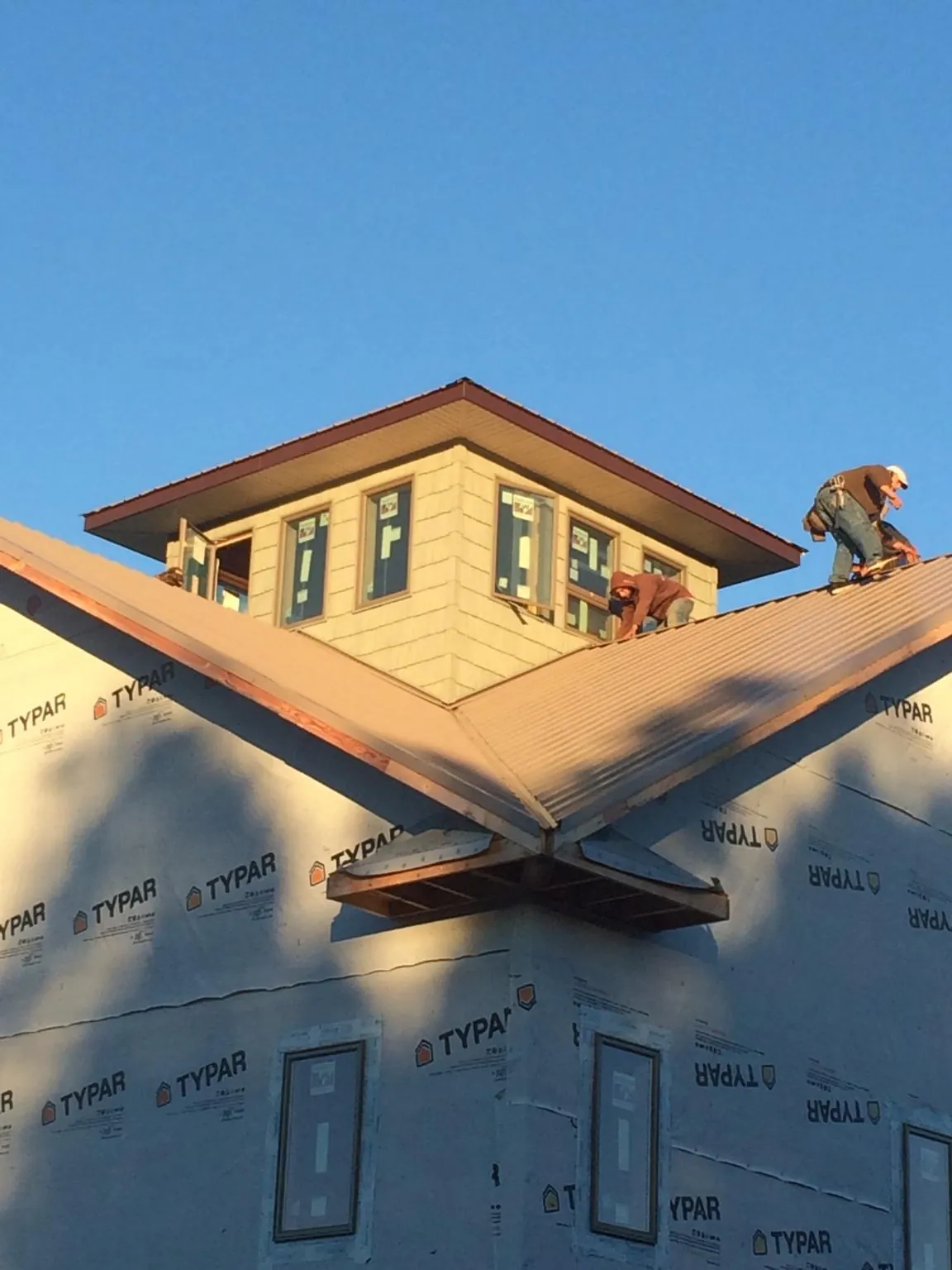 Roofers working around a rooftop cupola on a new metal roof at sunset — Roof Waterproofing in Lake Waccamaw by Roofing Brothers